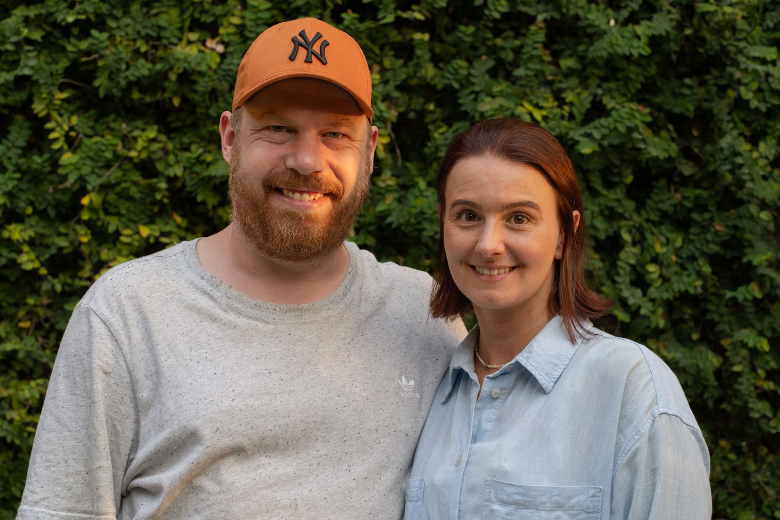 Nici und Ralph nebeneinander vor einer grünen Hecke, beide lächeln in die Kamera